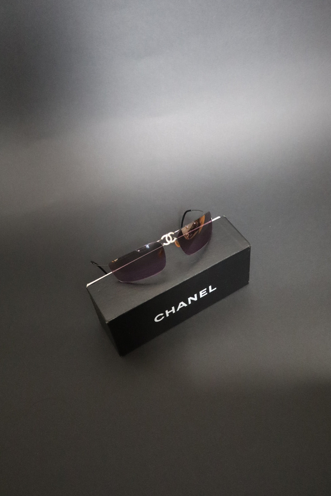 Chanel CC logo folding rimless wrap sunglasses with purple lenses